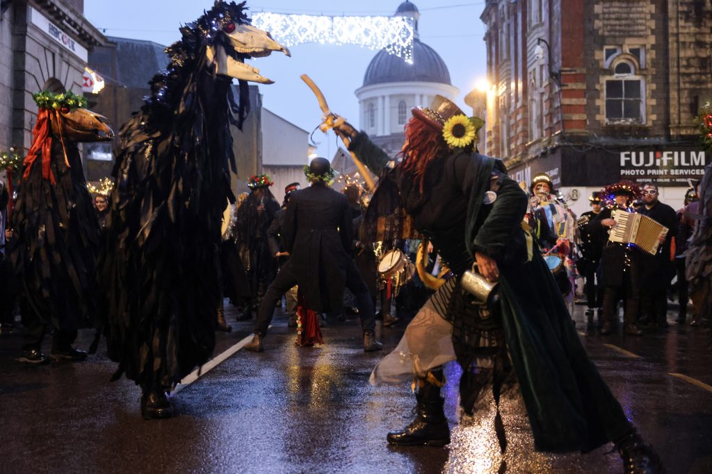 A Montol Oss being teased in the Greenmarket with the Market House  and Christmas Lights in the background